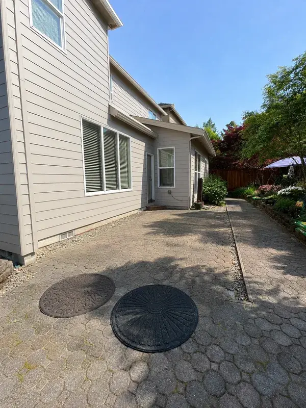 Open paver patio running along the side of the house, with nothing over it, in full sun