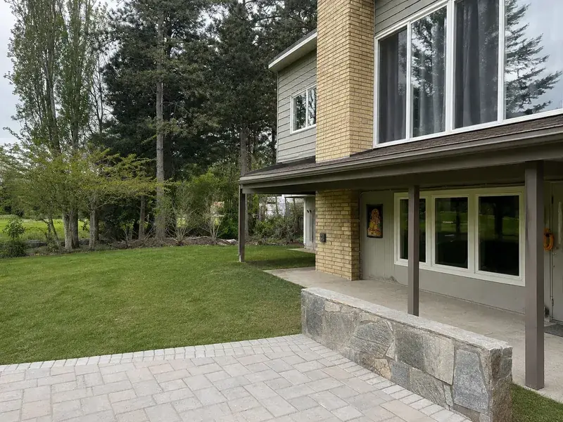 The back of the house before the build, lawn running up to a paver patio with no deck on it