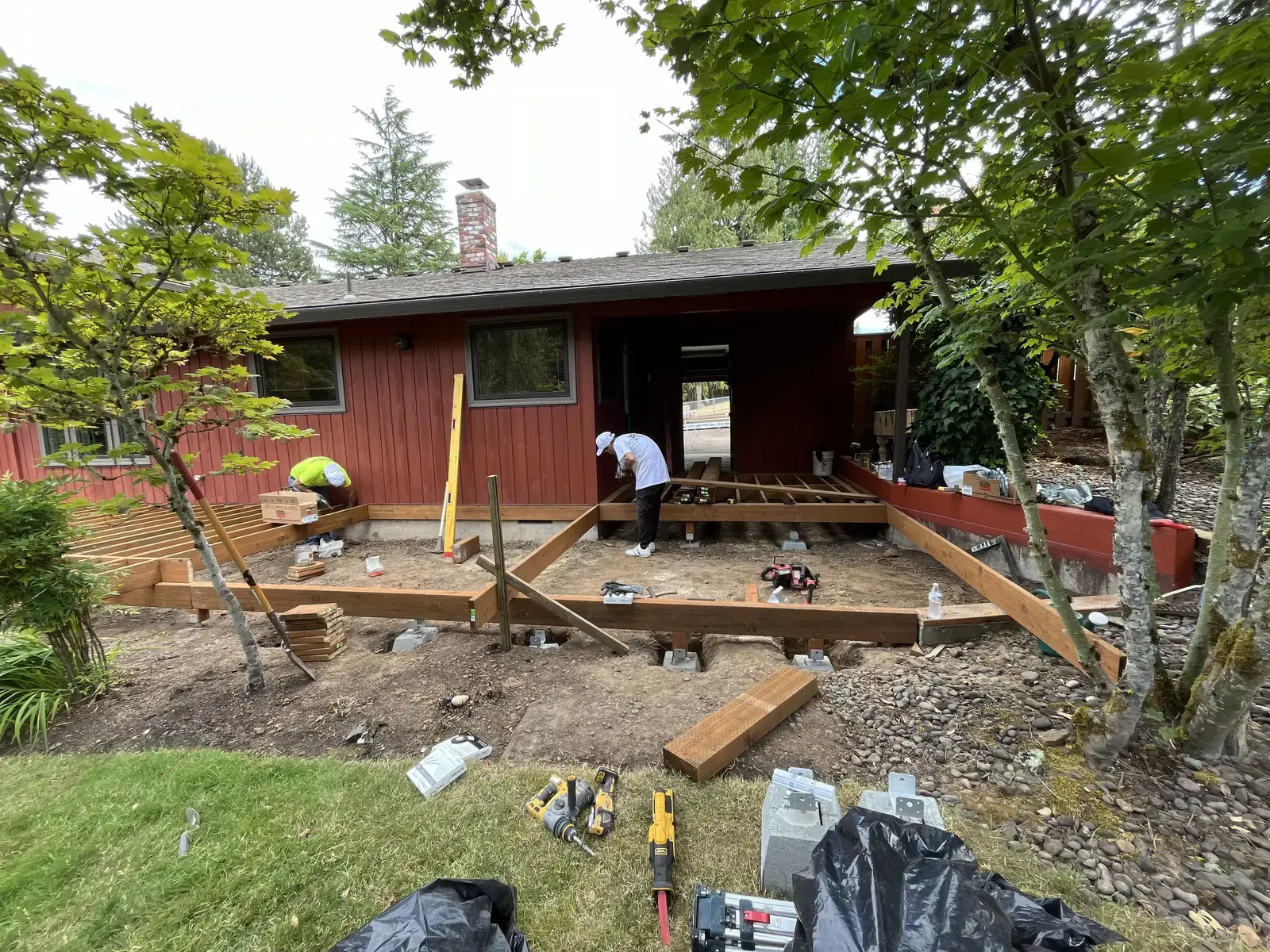 Crew setting out deck framing and footings around existing maples on a Portland lot