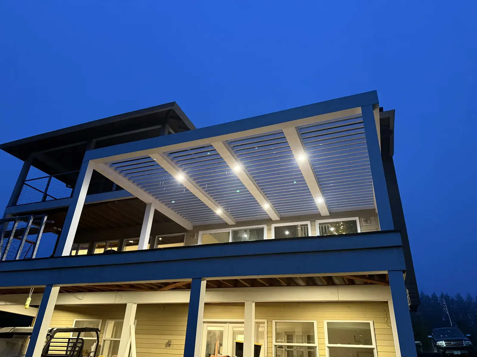Recessed lighting glowing through a slatted deck cover at dusk