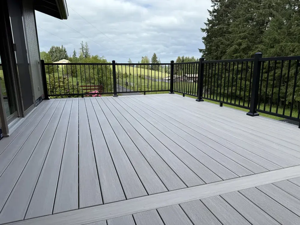 Light grey PVC deck with a picture-frame border and black railing overlooking open pasture