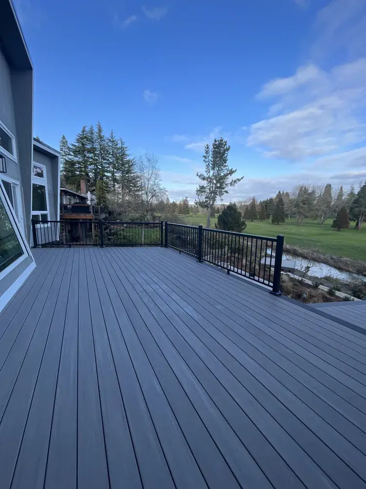Wide grey PVC deck with black aluminum railing looking out over a golf course