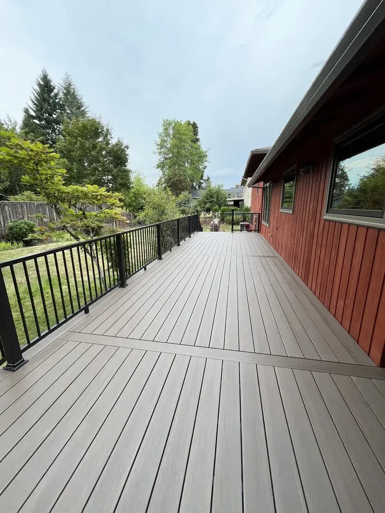 Grey-brown PVC deck with a contrasting inlay border alongside a red-stained home