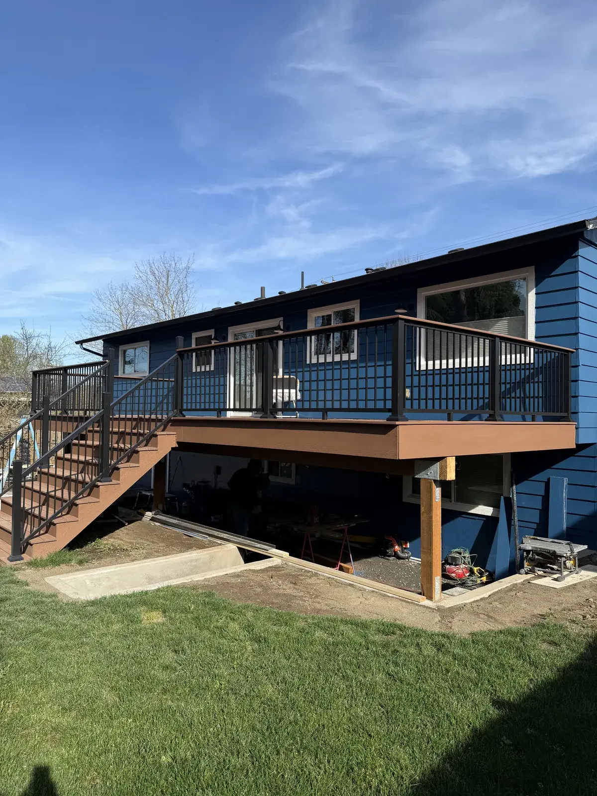 Raised PVC deck with black aluminum railing and stairs along the back of a blue home