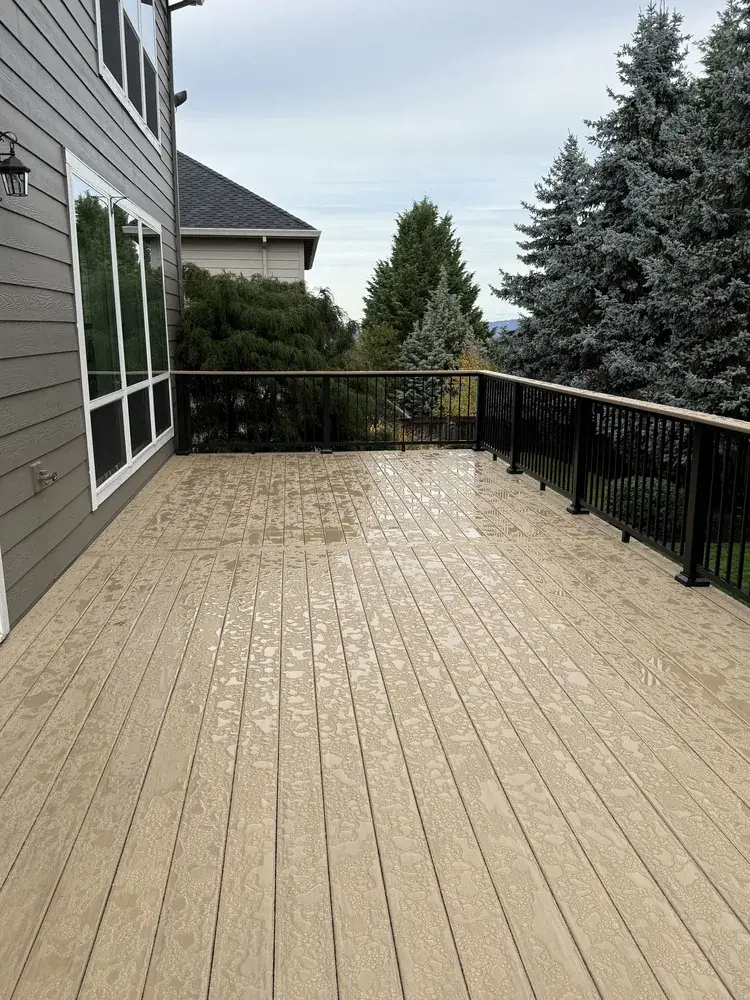 Rain beading on a sand-toned PVC deck with black aluminum railing on a hillside lot