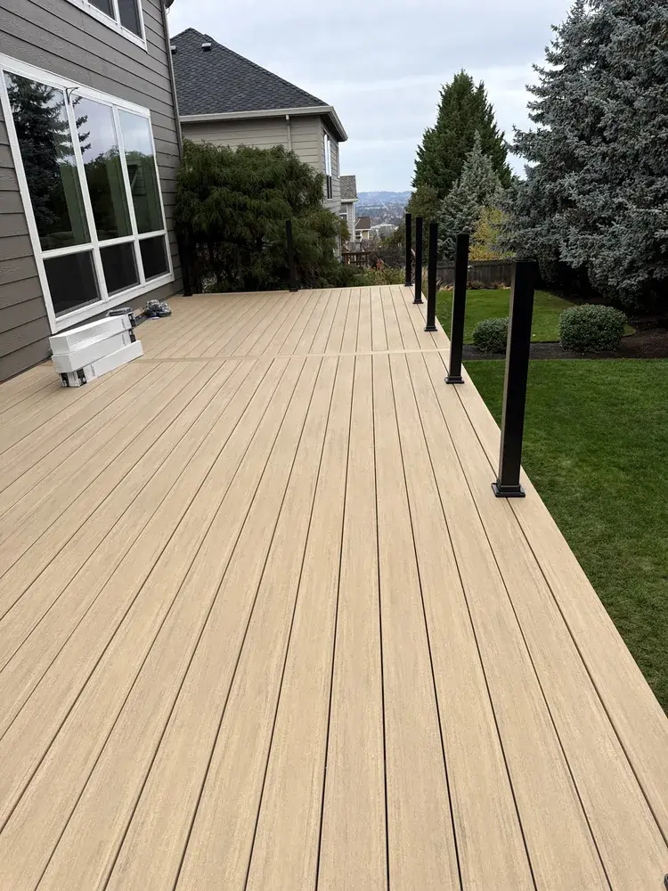 Sand-toned PVC deck with railing posts set, on a hillside lot with a valley view